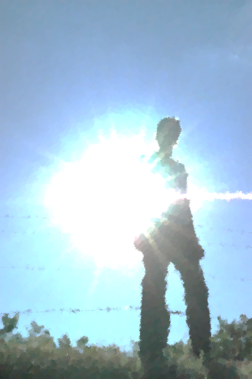 A person stands in shadow with the bright sun flaring behind her. The sky is blue.